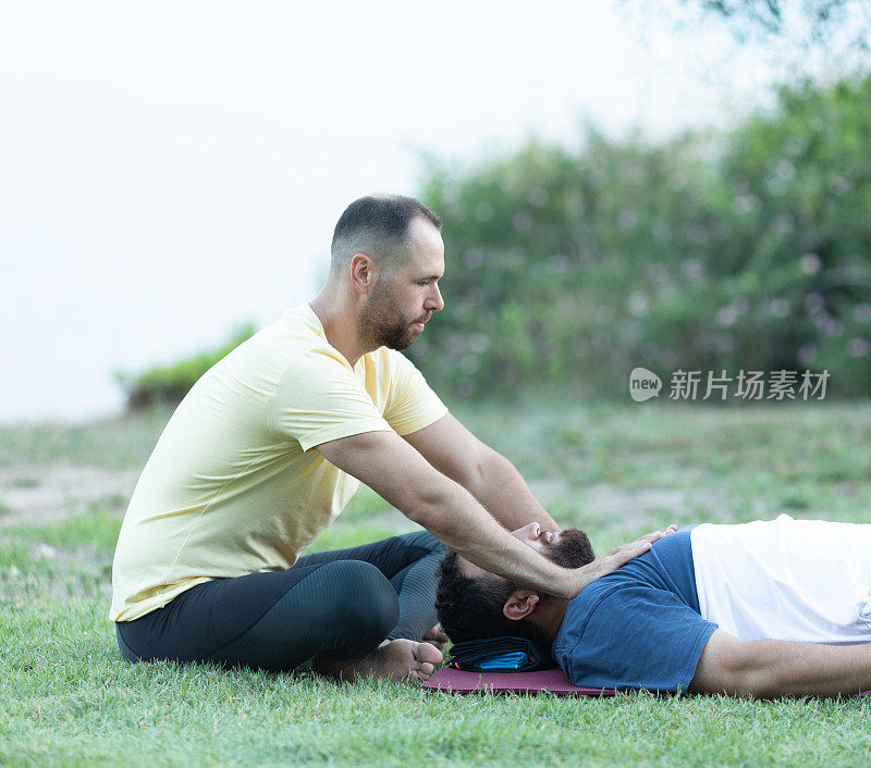 一个男人在给她的病人做瑜伽治疗