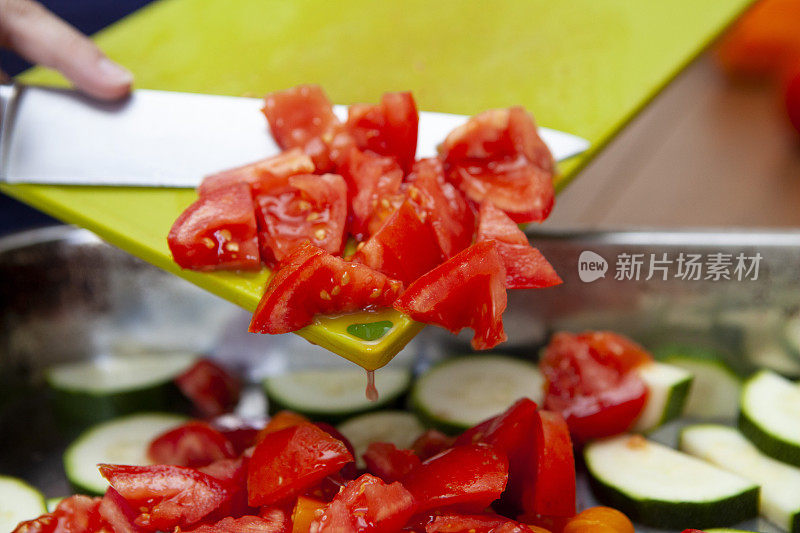 用刀将切好的番茄从砧板上切下来，放入不锈钢锅中