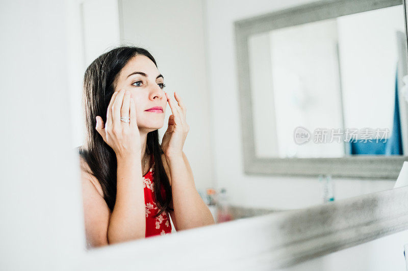 迷人的女人在她的三十多岁在家里的浴室化妆