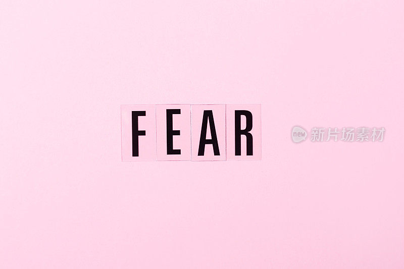 粉红色背景上的字母FEAR。负面情绪的概念。