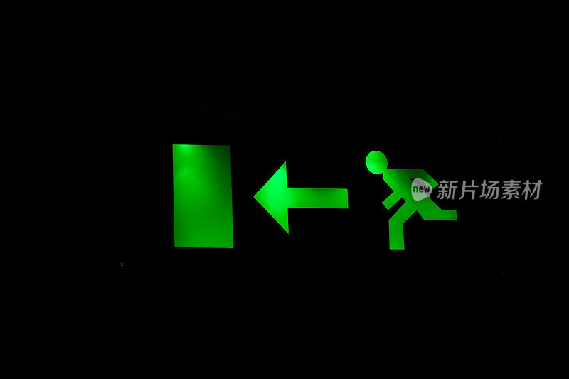 绿色的“出口在那里”标志在黑暗中发光