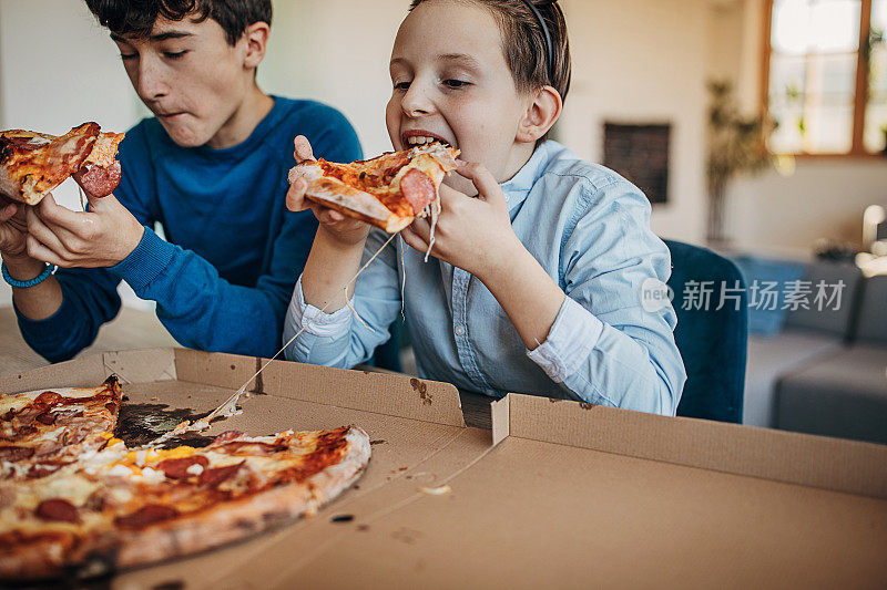 两个男孩一起吃披萨
