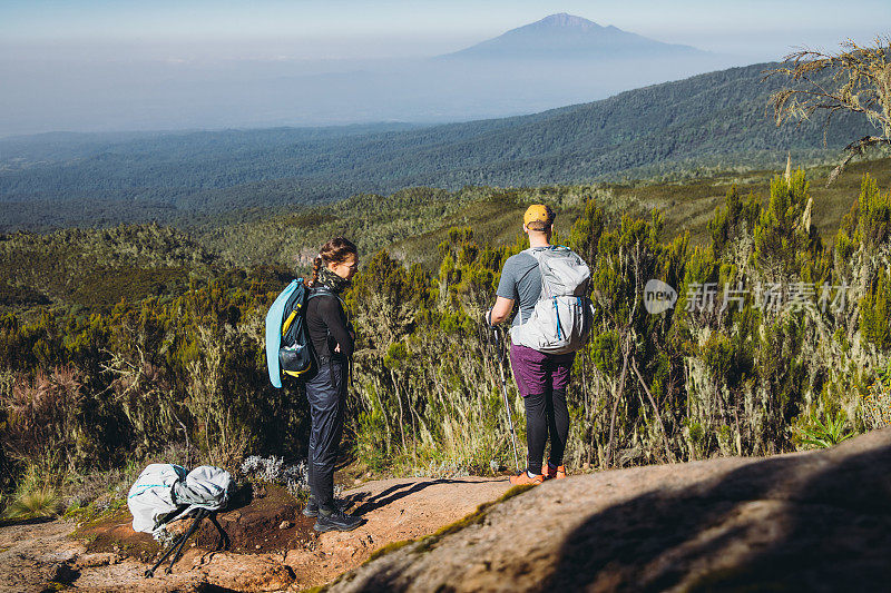 在乞力马扎罗山国家公园，男女徒步旅行者在山顶欣赏梅鲁山的美景