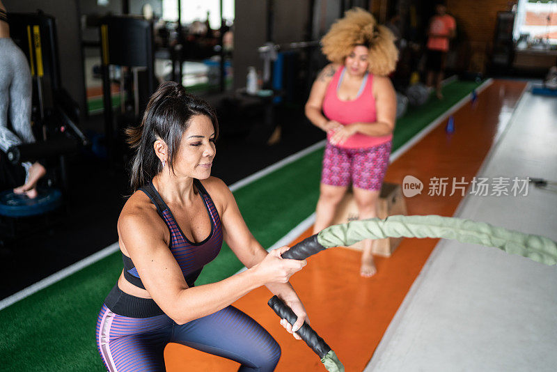 成熟的女人在健身房用格斗绳锻炼