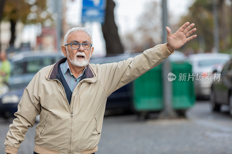 一位老人在城市街道上招手叫出租车。