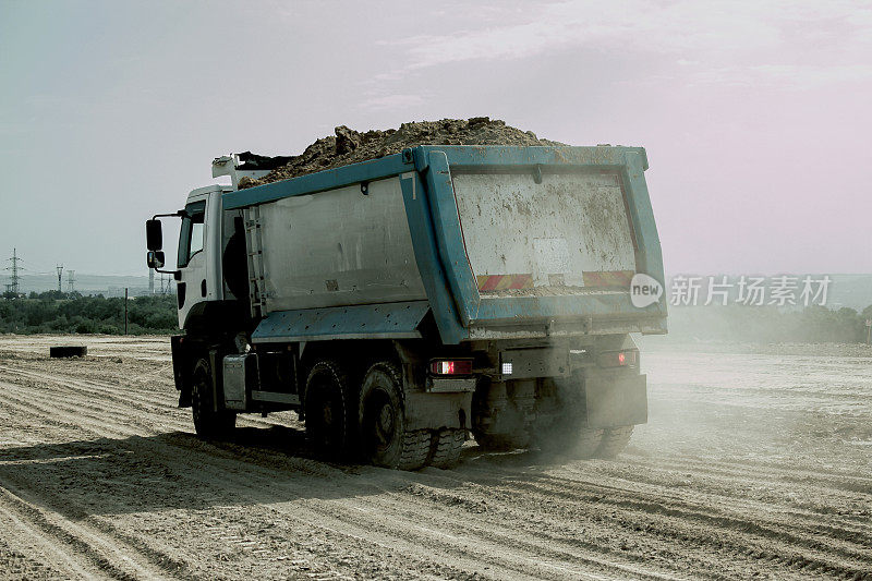 自卸车为修筑一条新公路卸载粘土。为新路打地基用的粘土。