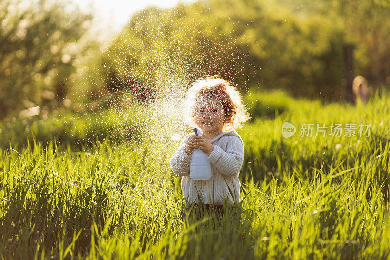 一个可爱的卷发女孩在农村浇水