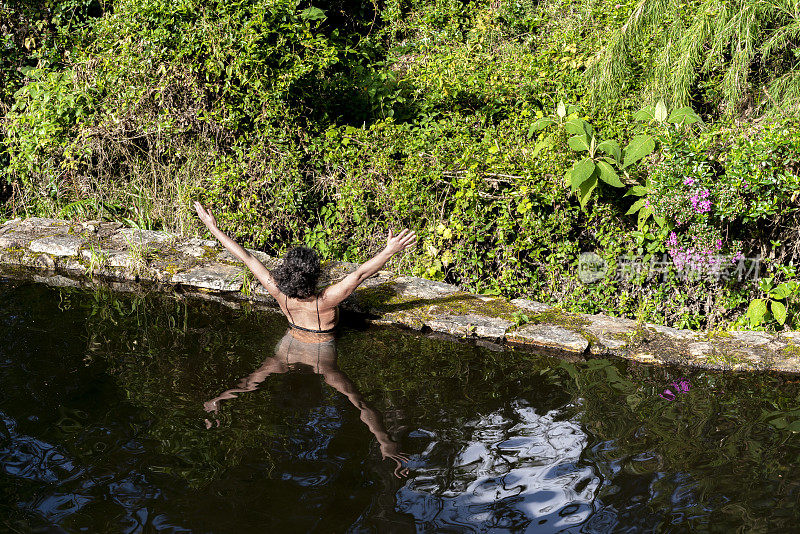 湖中一位非洲拉丁妇女向大自然张开双臂