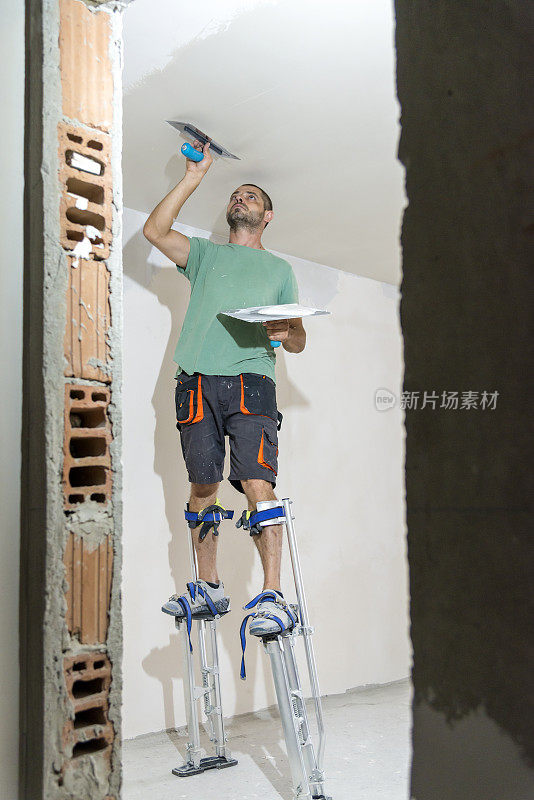 建筑工人用灰泥粉刷房间的天花板。