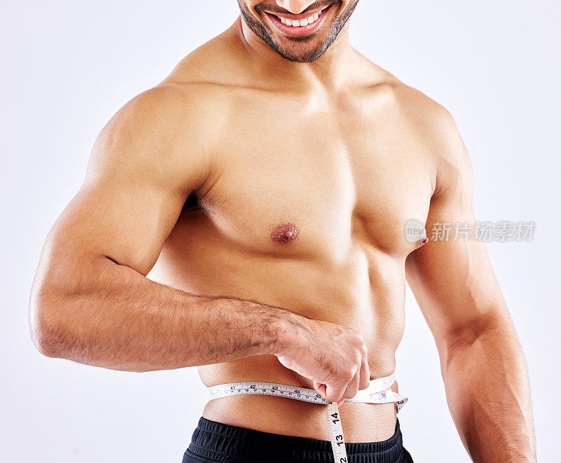 一名男性运动员在白色背景下测量自己的腰围