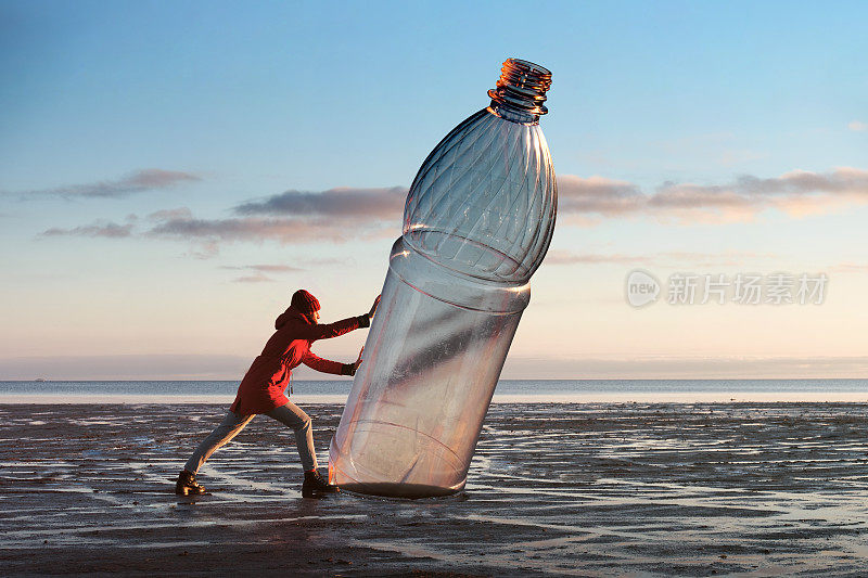 一个女人正把一个巨大的塑料瓶推到岸边。