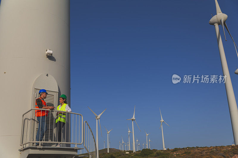 两名工程师在大流行期间在风电场工作风力涡轮机