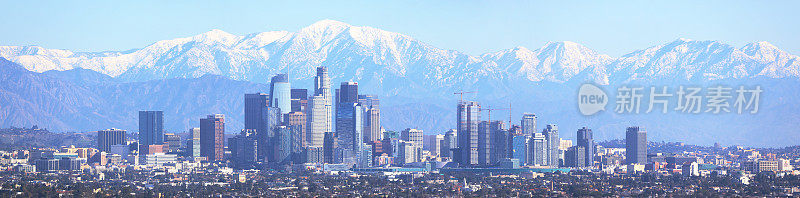 洛杉矶天际线全景图，背景是白雪覆盖的圣加布里埃尔山脉