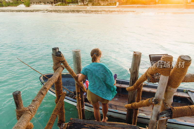 在明亮的日落时分，在热带岛屿乘船旅行的女游客