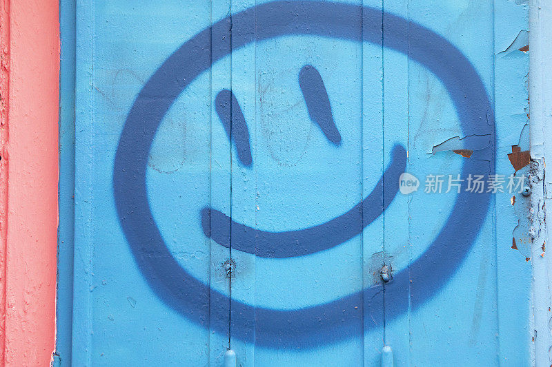 蓝色的墙上画着拟人化的蓝色笑脸