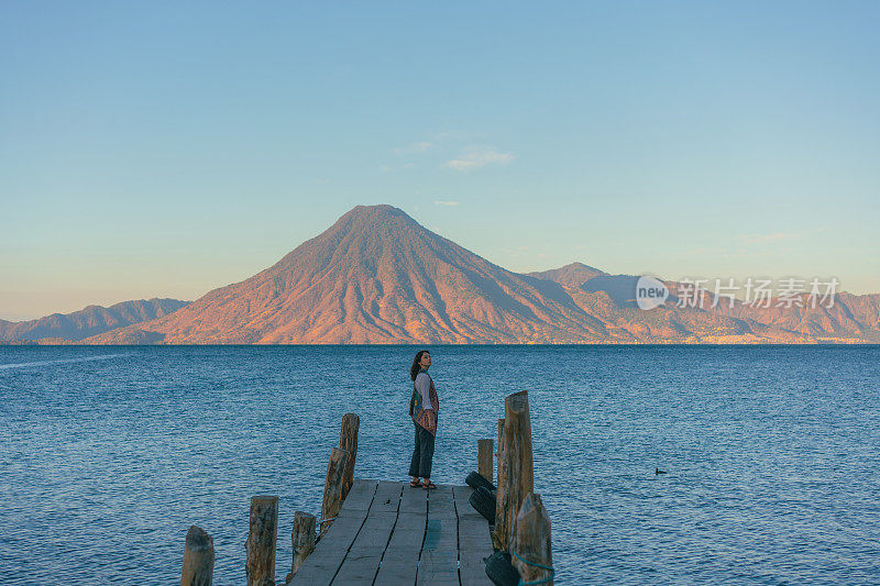 日落时分，站在危地马拉阿提特兰湖码头上的女人