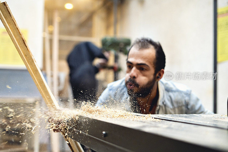 木匠正在吹木工车间机器上的木屑。
