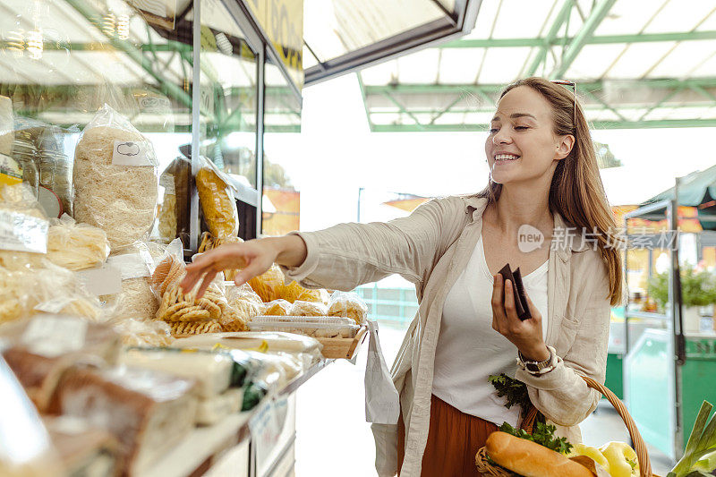 女人提着装满食品杂货的篮子，正在买食物