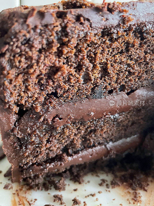 全帧图像的巧克力软糖蛋糕显示海绵层被厚厚的ganache填充在白色的盘子上，重点放在前景