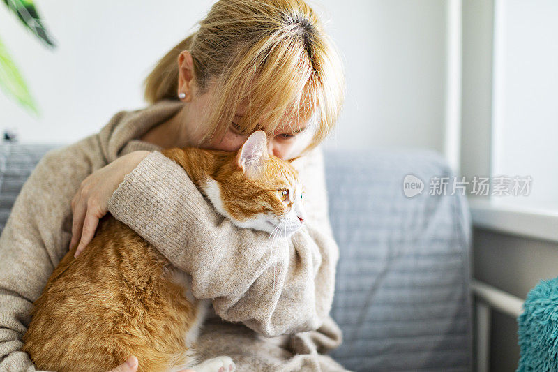 年轻的成年妇女和姜黄色的猫在家里