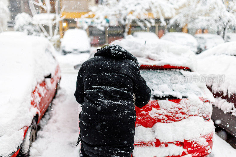 一名男子在推一辆陷在雪里的车。