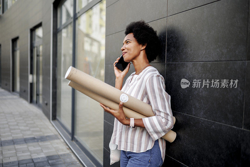 微笑的建筑师在街上使用她的智能手机