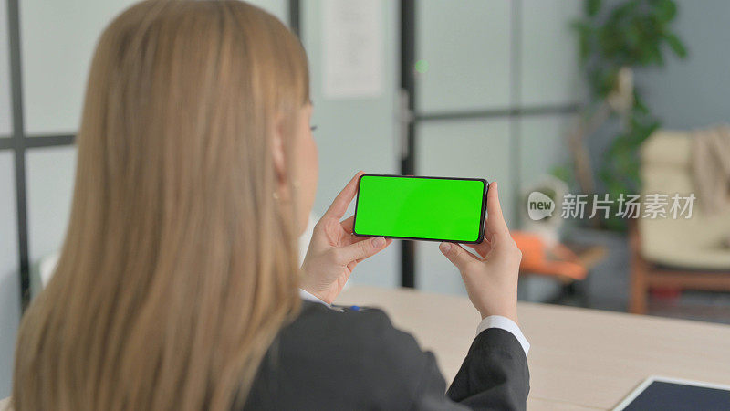年轻的女商人用色度键观看智能手机