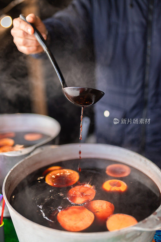 集市上用肉桂和柑橘在大锅里酿造的圣诞热葡萄酒。烹饪传统的圣诞和新年饮料