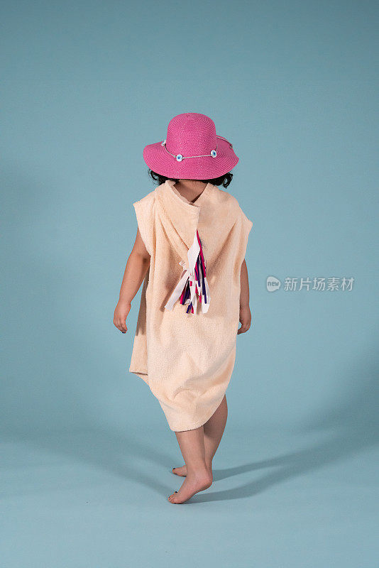 女孩在走路，她有粉红色的帽子在蓝色的背景垂直的孩子情绪仍然