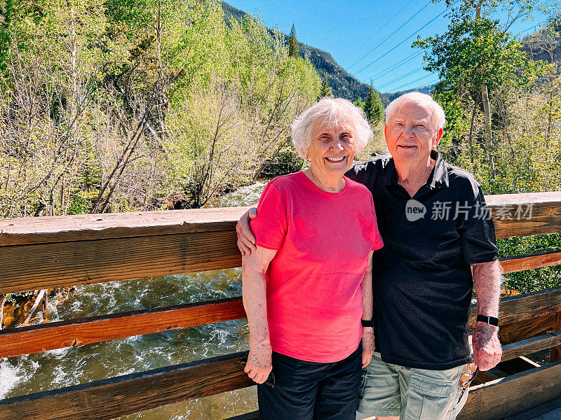 在科罗拉多州山区旅行时，一对快乐的老年夫妇一起站在桥上