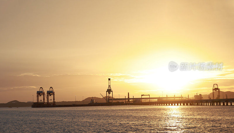 傍晚在港口、海上、河码头。工业起重机的轮廓。港口风景。明亮的夕阳，剪影动力起重机在海港，进出口的概念。