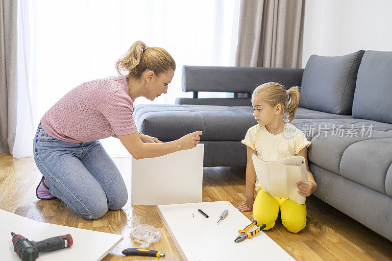 一个小孩和一个女人在客厅里组装家具