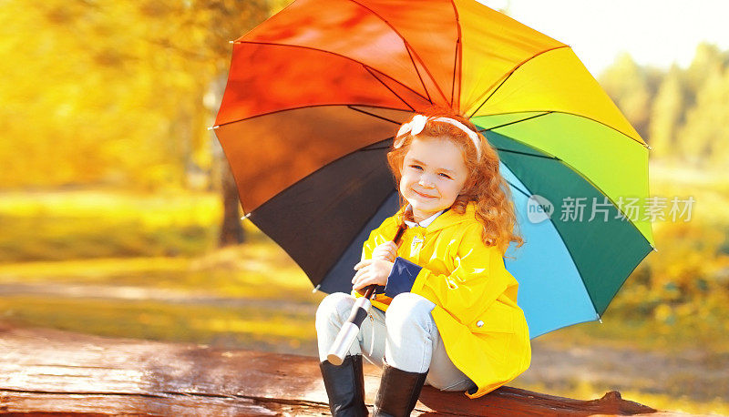 快乐的小女孩在阳光明媚的秋天公园里撑着五颜六色的伞