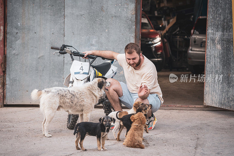 机械师在机械师车库前，在发动机测试后抚摸流浪狗。