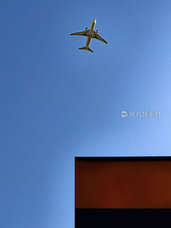 一架商用飞机在湛蓝的天空飞过一座大楼