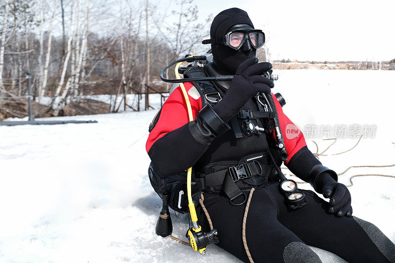 潜水员站在冰洞边缘，准备潜入水中