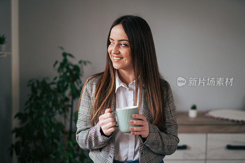 漂亮的女商人在家里的客厅里喝咖啡