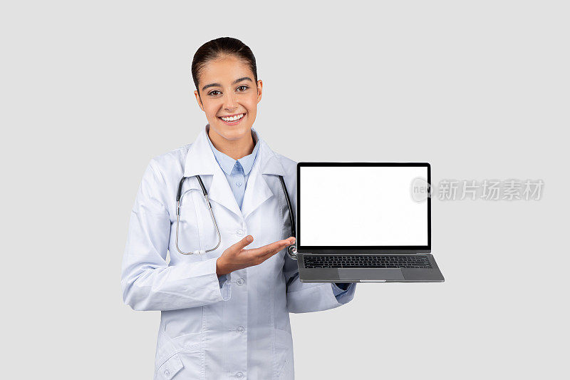 阳性的白衣白人女医生用手指着电脑