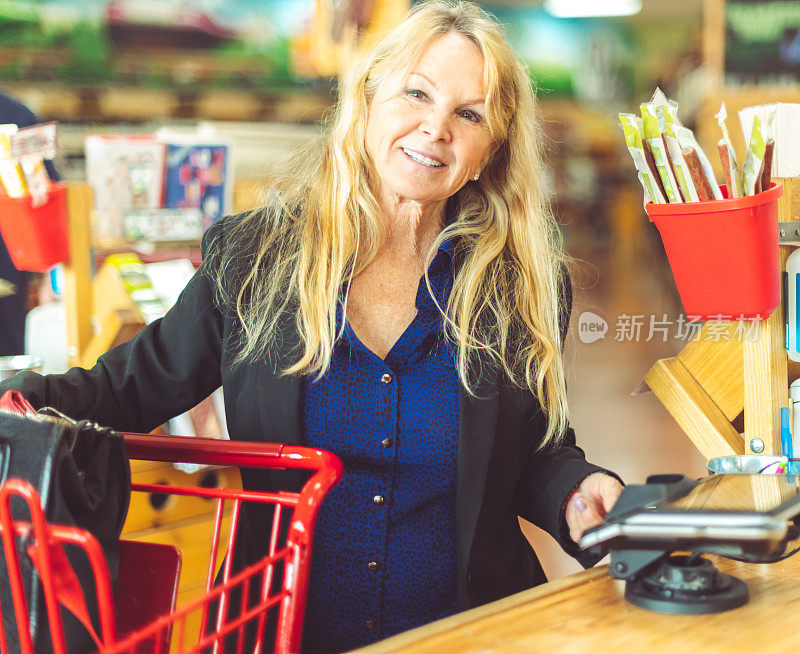 一位年长的成年妇女在杂货店购物时使用键盘完成交易