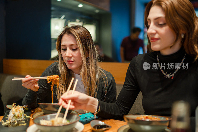 年轻女子和她的朋友出去吃面条吃晚餐