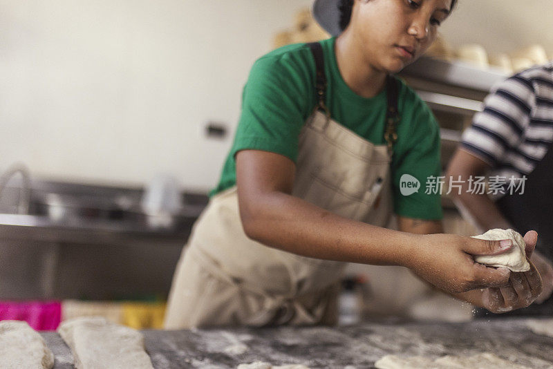 菲律宾女面包师在面包房的厨房里揉面，做牛角面包和糕点