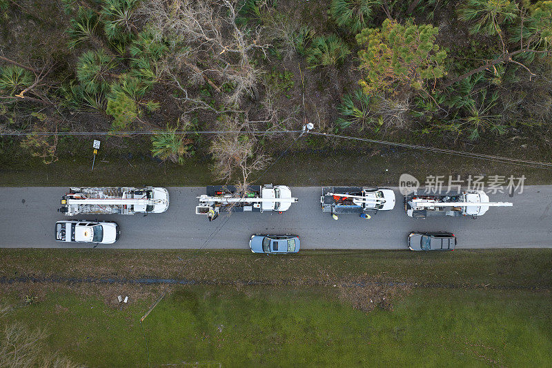 飓风过后，电工工人在佛罗里达居民区用铲斗卡车修理损坏的电线