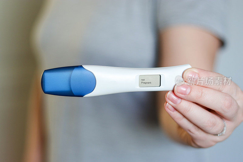 一名妇女拿着数字阴性妊娠测试的特写