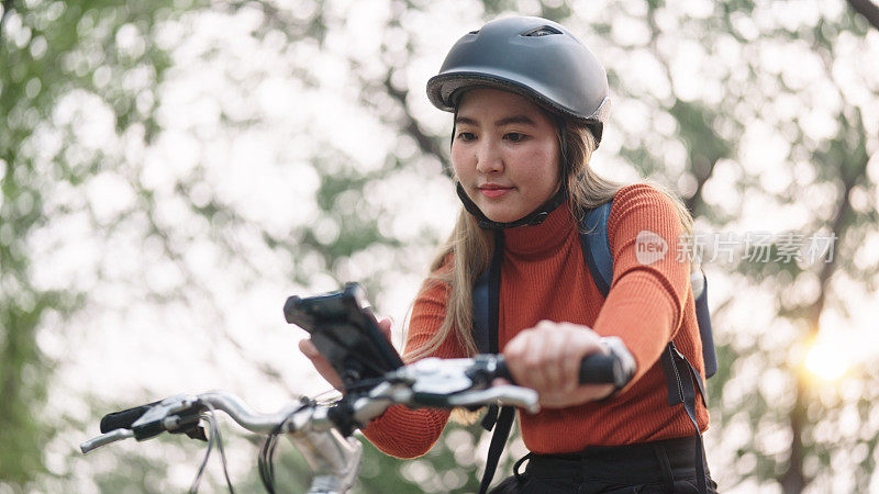 女子骑自行车旅行时使用智能手机。