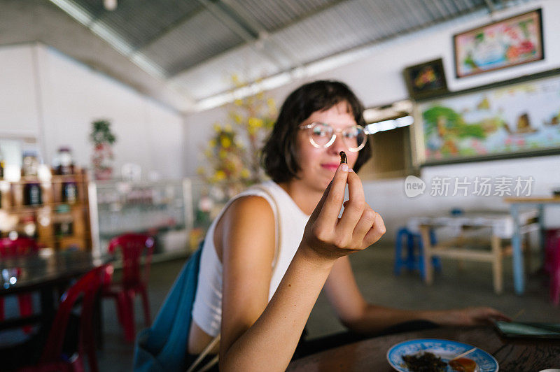 一位女游客正在品尝越南美食——炸蟋蟀