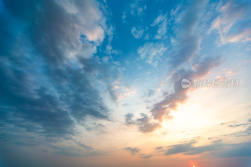 戏剧性的日落天空与云:一个美丽的显示光和颜色与蓝色，白色和橙色色调，捕捉日落的宁静时刻。