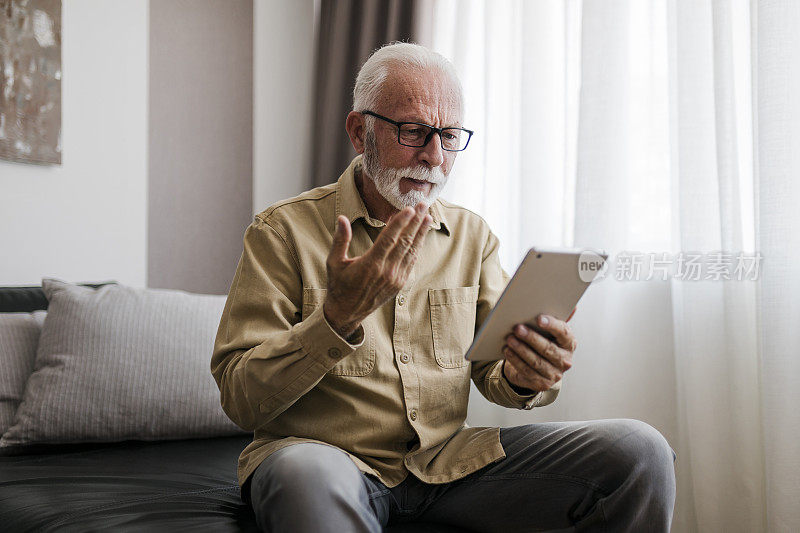 愤怒的老人祖父使用数字平板电脑，搜索网页，加载feed，社交媒体。和孩子们，孙子们交流