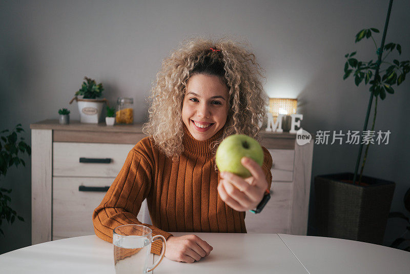 漂亮的卷发女人手里拿着一个青苹果