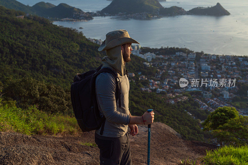 一个徒步旅行者正在享受他到达山顶的成就，并欣赏着壮丽的景色