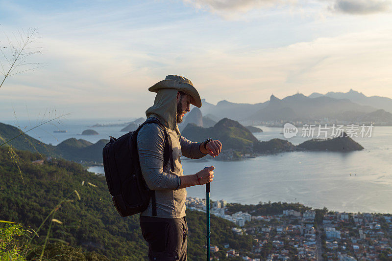 一个徒步旅行者正在享受他到达山顶的成就，并欣赏着壮丽的景色